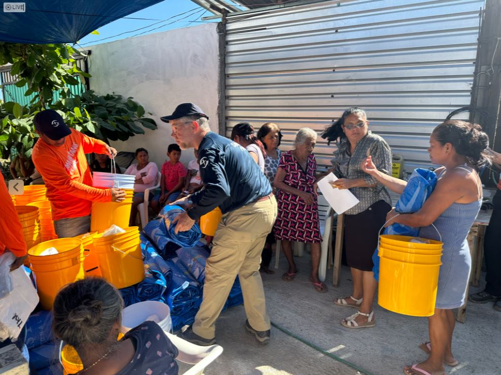 men working handing buckets and tarps to women in a line.