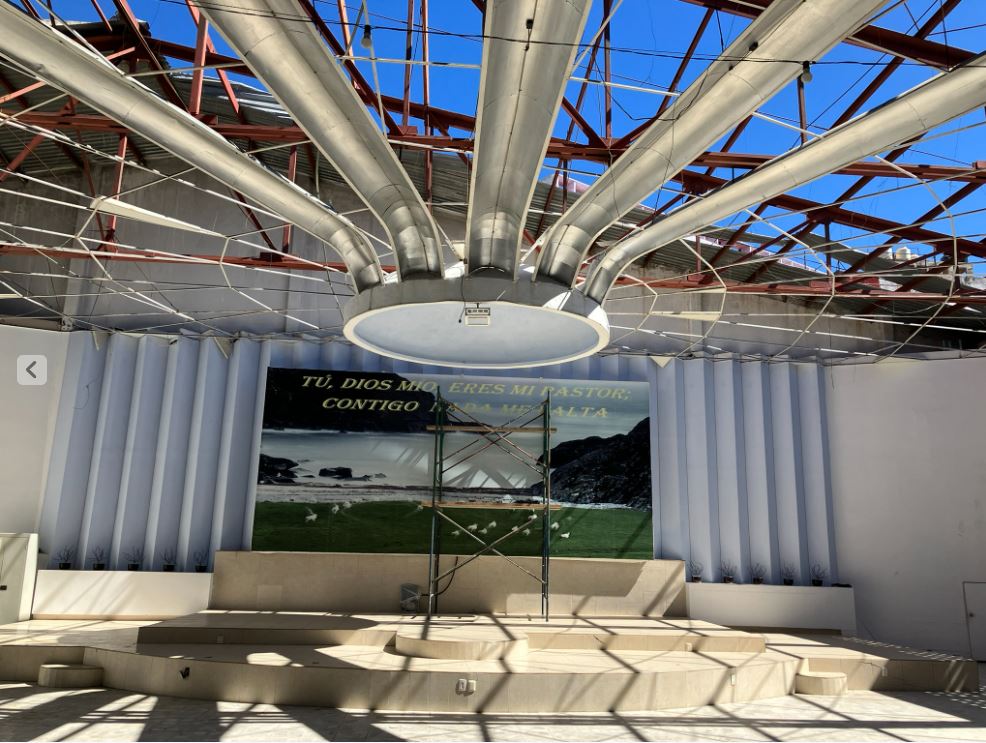 Large modern church sanctuary, rafters completely open to blue sky.